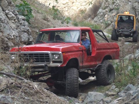 1978 Ford Bronco - A red 1978 Ford Bronco navigates a challenging rocky terrain, with another vehicle following behind.