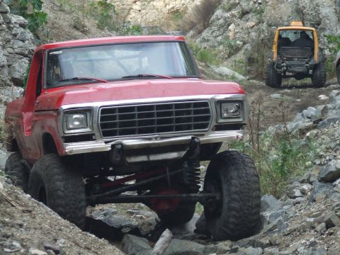 1978 Ford Bronco - A red 1978 Ford Bronco navigates a rocky trail, with another off-road vehicle visible in the background.