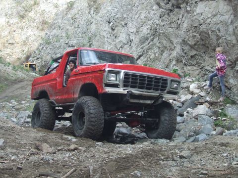 1978 Ford Bronco - Modified 1978 Ford Bronco navigating a rocky trail with a person standing on the rocks nearby.