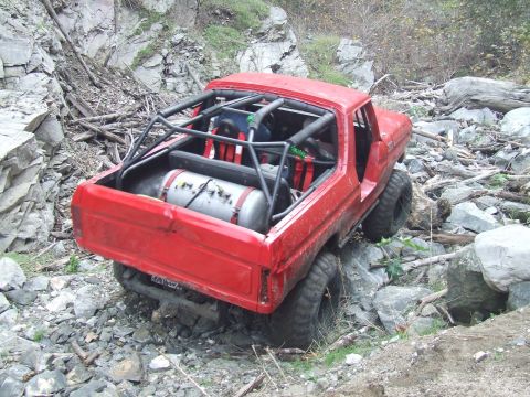1978 Ford Bronco - A modified 1978 Ford Bronco tackles a challenging rocky trail, equipped with a roll cage and auxiliary tank.