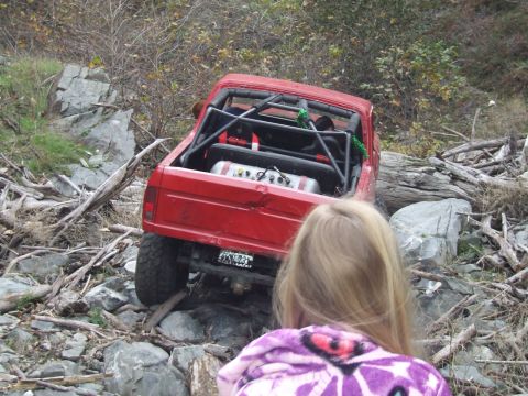 1978 Ford Bronco - Modified 1978 Ford Bronco tackling rough terrain with a roll cage and auxiliary fuel tank visible.