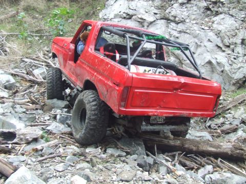 1978 Ford Bronco - This red 1978 Ford Bronco navigates a challenging rocky terrain, demonstrating its off-road capabilities.