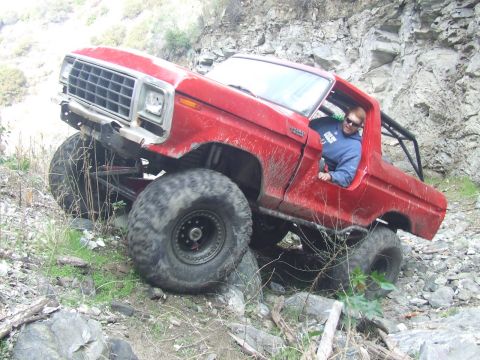 1978 Ford Bronco - A red 1978 Ford Bronco navigates a challenging rocky terrain with a driver behind the wheel.