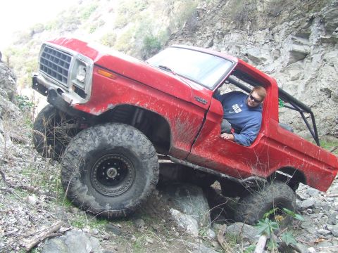 1978 Ford Bronco - A red 1978 Ford Bronco is shown navigating a challenging rocky trail with a driver inside.