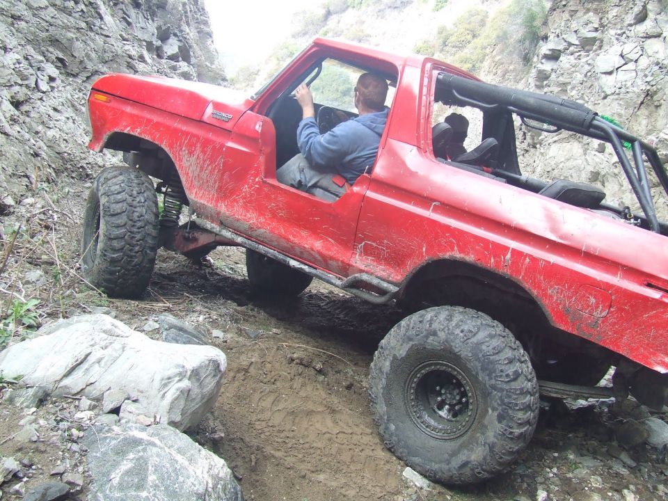 Red 1978 Ford Bronco navigating rocky terrain