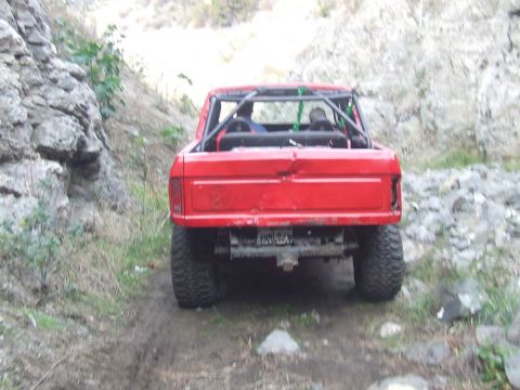 1978 Ford Bronco - Rear view of a red 1978 Ford Bronco modified for off-road use, a roll cage and large tires.