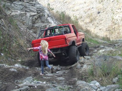 1978 Ford Bronco - Modified 1978 Ford Bronco tackling a challenging rocky terrain with a young girl watching.