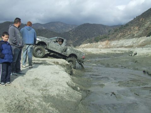 1978 Ford Bronco - Pickup truck stuck in mud, with onlookers observing the difficult situation.
