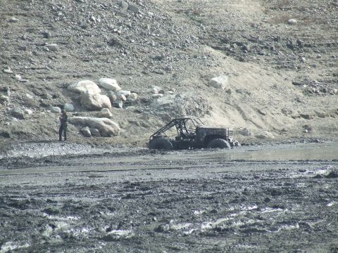 1978 Ford Bronco - An off-road vehicle is stuck in deep mud in a desolate, rocky area.