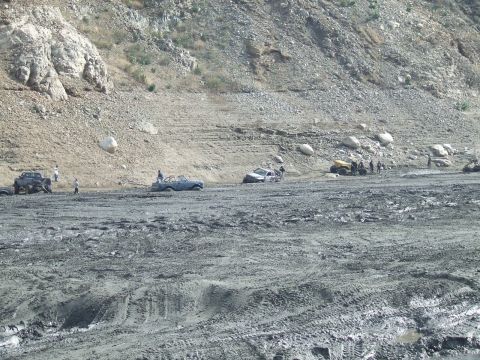 1978 Ford Bronco - Multiple vehicles are bogged down in a muddy, rocky terrain, with several people observing the scene.