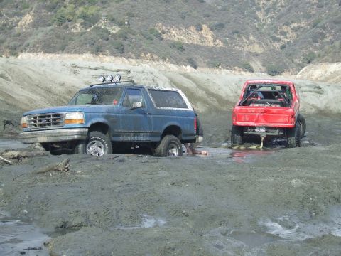 1978 Ford Bronco - Two off-road vehicles are stuck in thick mud after an apparent off-roading incident.