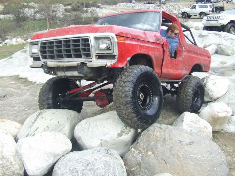 1978 Ford Bronco - This modified SUV is navigating a rocky trail with its large tires.