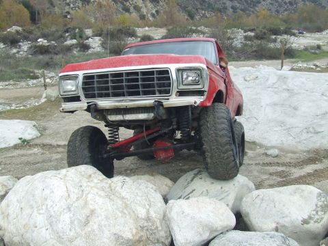 1978 Ford Bronco - This lifted 1979 Ford F-Series truck is shown off-roading over large rocks in a dry riverbed.