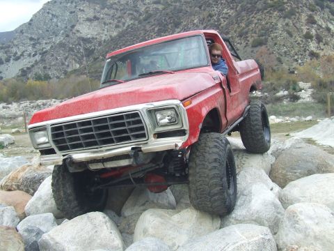 1978 Ford Bronco - A red pickup truck navigates a rocky terrain, its off-road capabilities.