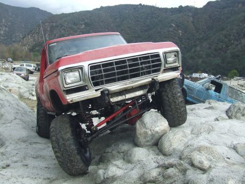 1978 Ford Bronco - A red 1978 Ford Bronco navigates a rocky terrain, with another vehicle visible in the background.