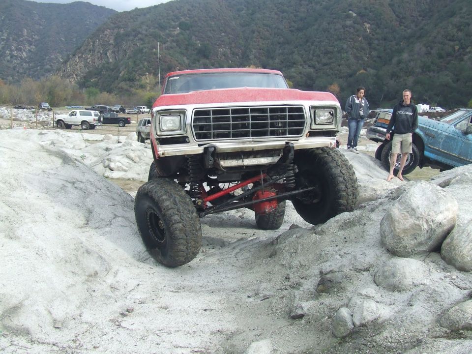 Red 1979 Ford F-Series truck with large tires on rocky terrain
