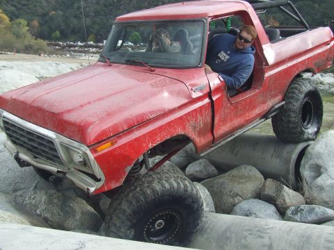 1978 Ford Bronco - A red 1978 Ford Bronco navigates a challenging off-road course with large tires and a lifted suspension.