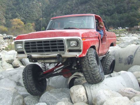 1978 Ford Bronco - This modified 1978 Ford Bronco is shown off-roading over large rocks and concrete pipes.