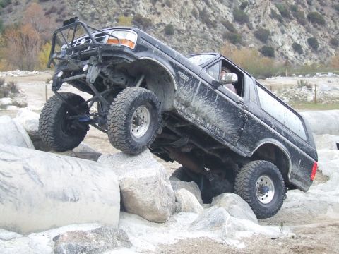 1978 Ford Bronco - Modified black Ford Bronco tackles a rocky obstacle course.