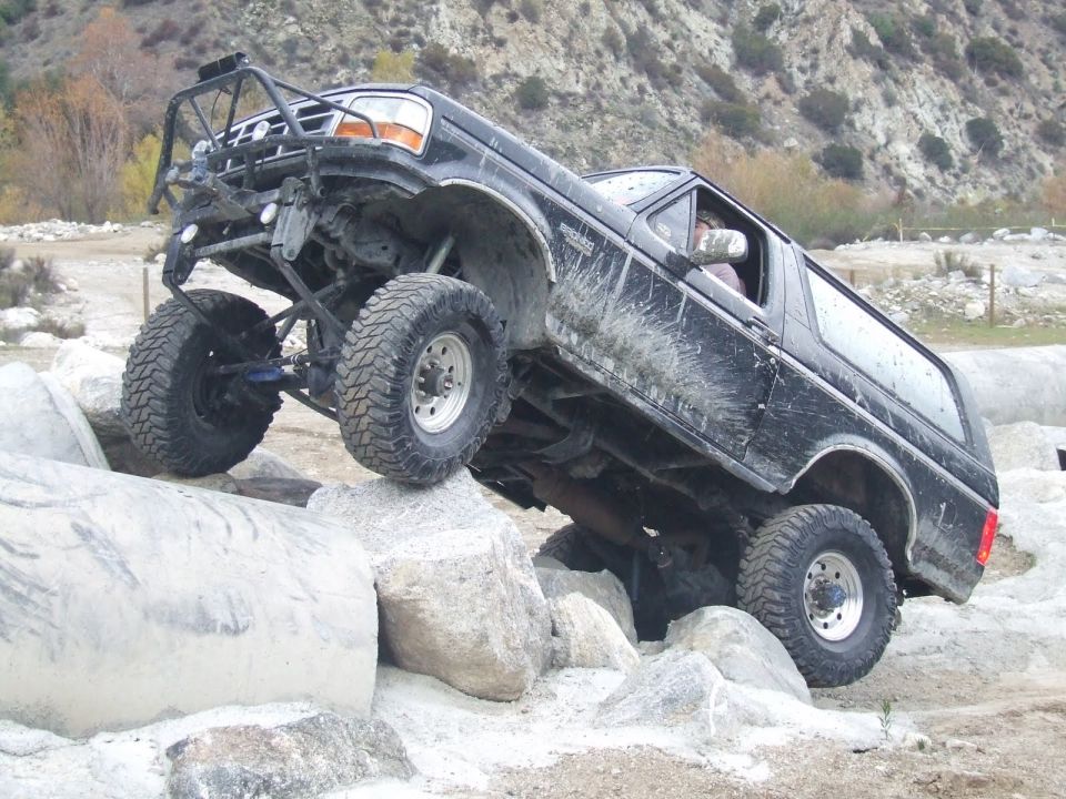 Black Ford Bronco with off-road modifications navigating large rocks