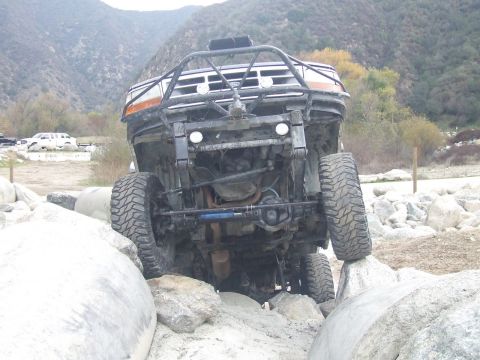 1978 Ford Bronco - This heavily modified off-road vehicle is shown from the front, with its tires positioned on large rocks.