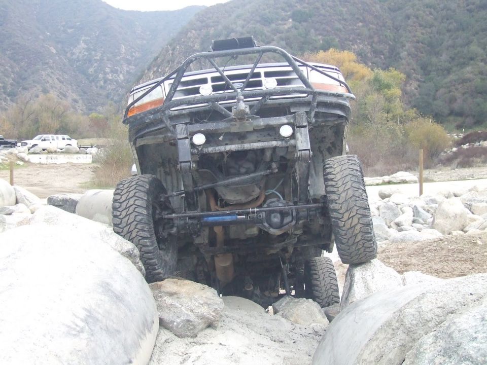Front view of an off-road vehicle with a brush guard, navigating large rocks