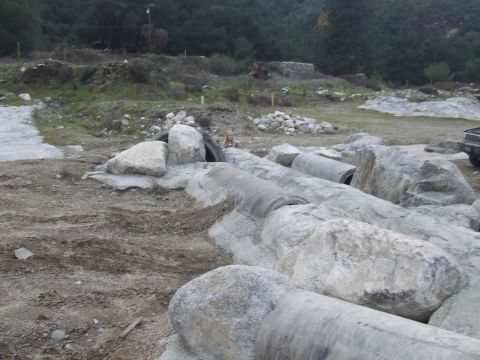 1978 Ford Bronco - A black Jeep Wrangler is visible on the right side of the frame, parked on a rocky and uneven surface.