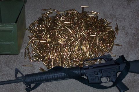 1980 Ford Bronco - A pile of brass cartridges and an assault rifle sit on a carpeted floor next to an ammunition can.