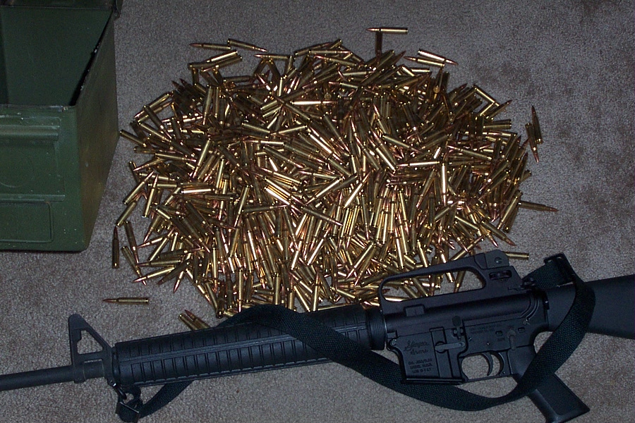 AR-15 style rifle with a large pile of cartridges next to a green ammo can