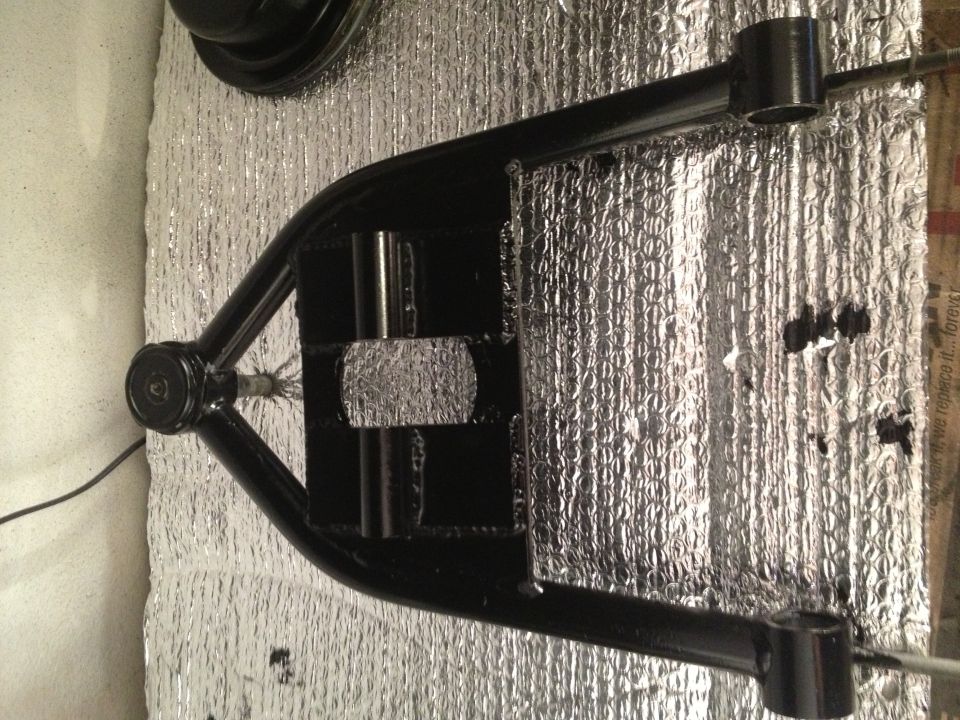 Black painted control arm with silver insulation behind it. SuperMotors logo visible