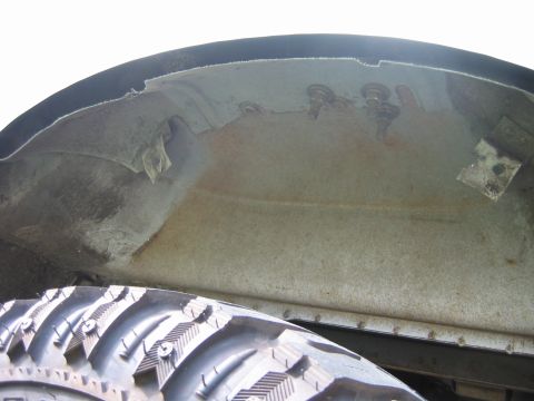 1992 Ford Bronco - Close-up view of a vehicle's wheel well interior, showing fasteners and signs of wear.