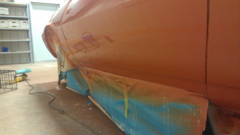 1973 Chevrolet Camaro - The side of an orange vehicle is masked with blue tape and paper for painting.