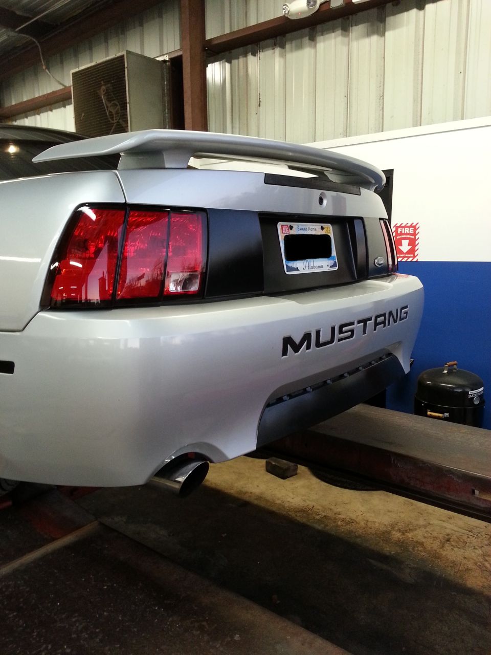 Rear of a silver 2004 Ford Mustang on a lift, showing taillights and spoiler