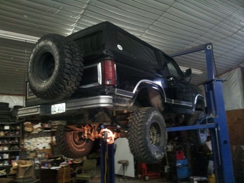 1986 Ford Bronco - This SUV is being worked on in a garage, lifted for maintenance.