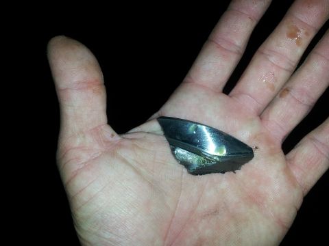 1986 Ford Bronco - A detached piece of chrome trim, possibly from a vehicle, is held in a person's palm.
