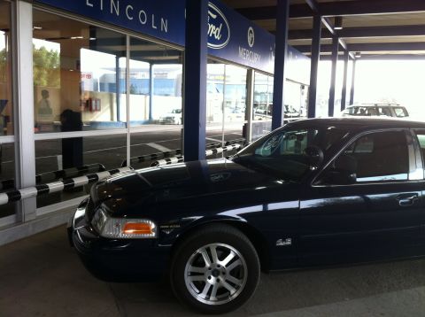 2007 Ford Crown Victoria - A dark blue 2007 Ford Crown Victoria is parked outside a Ford, Lincoln, and Mercury dealership.
