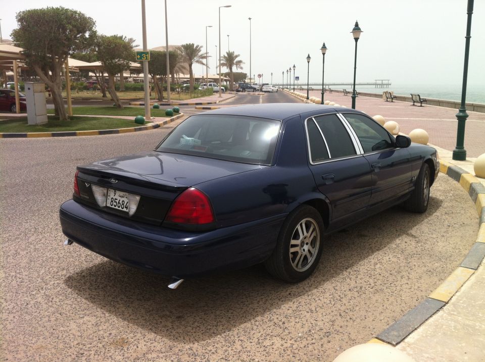 Dark blue sedan parked by the water, with a license plate showing 85684