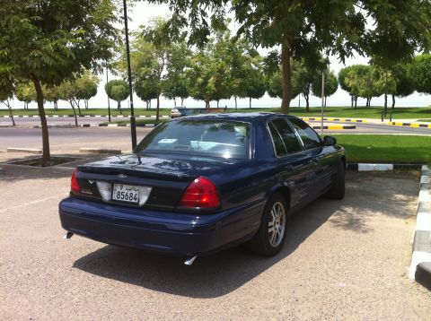 2007 Ford Crown Victoria - A dark blue 2007 Ford Crown Victoria is parked in an outdoor lot near a body of water.