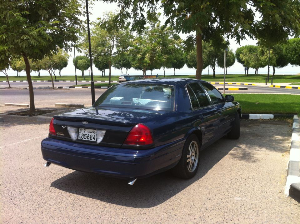Dark blue 2007 Ford Crown Victoria parked in a lot with trees and water in the background