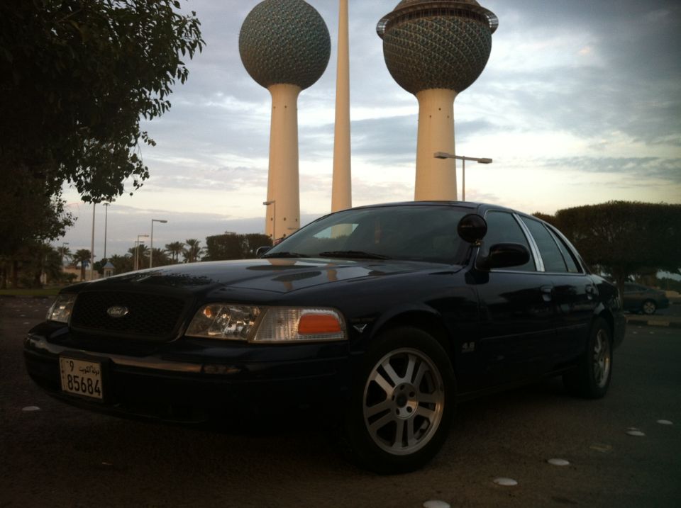 Black Ford Crown Victoria Police Interceptor parked with Kuwait Towers in background