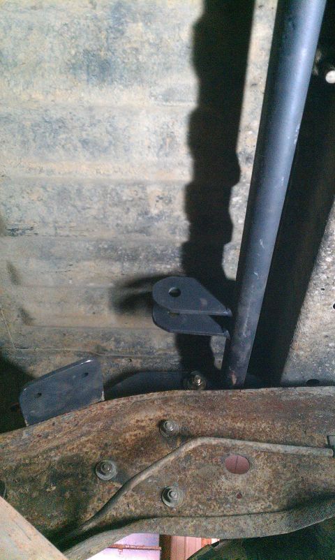 1995 Ford Bronco - Close-up of a rear shock hoop mount attached to a heavily rusted vehicle frame.