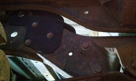 1995 Ford Bronco - Underside view of a vehicle's frame and suspension components, showing rust and a bolted bracket.