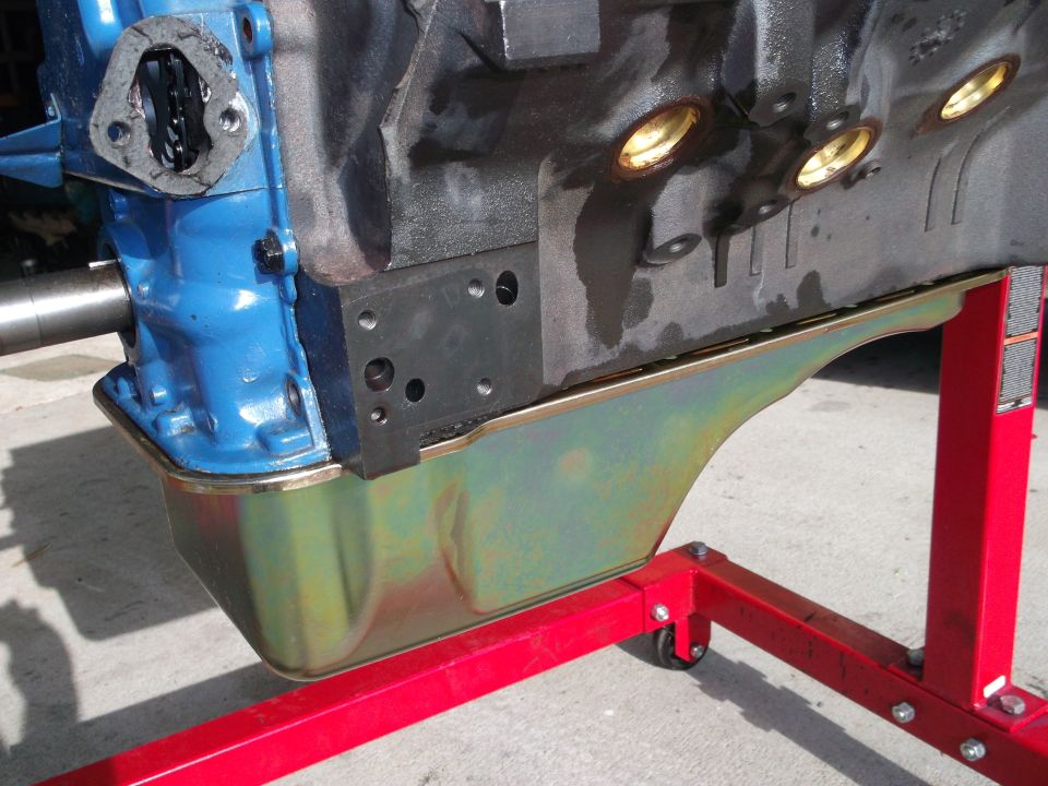Engine block on red stand, showing oil pan and blue pump housing