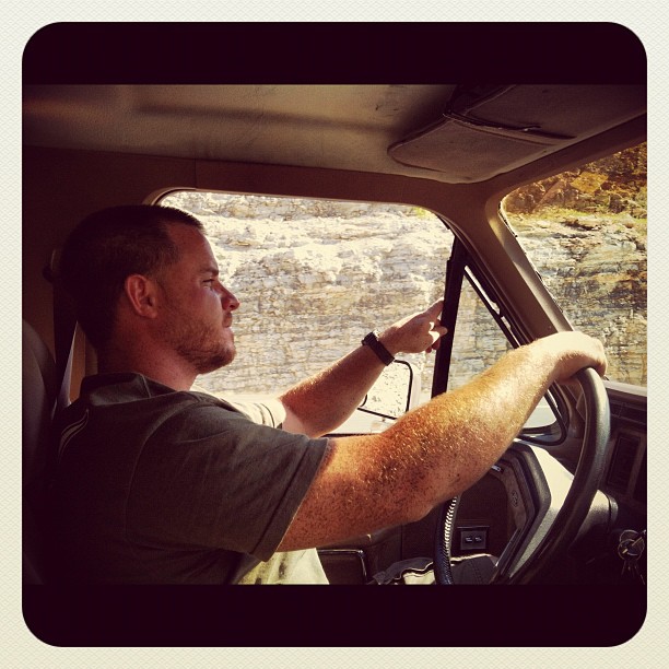 Man driving a 1986 Ford Bronco, pointing out the window