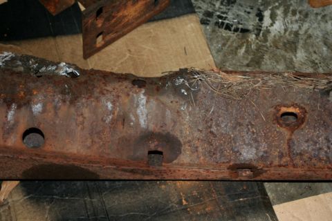 1976 Ford Ranchero - A heavily rusted vehicle frame section is shown, with pine needles visible on top.