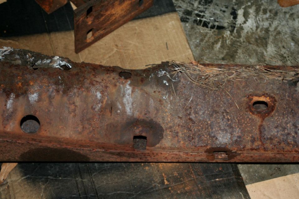 Rusted vehicle frame section with pine needles
