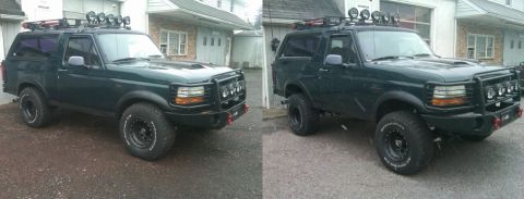 1993 Ford Bronco - This dark green Ford Bronco has a lift kit, roof rack, and bull bar, and is parked in front of a garage.