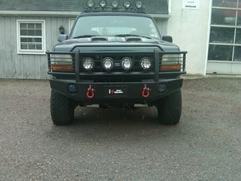 1993 Ford Bronco - Front view of a black Ford Bronco with a custom bumper and multiple auxiliary lights.