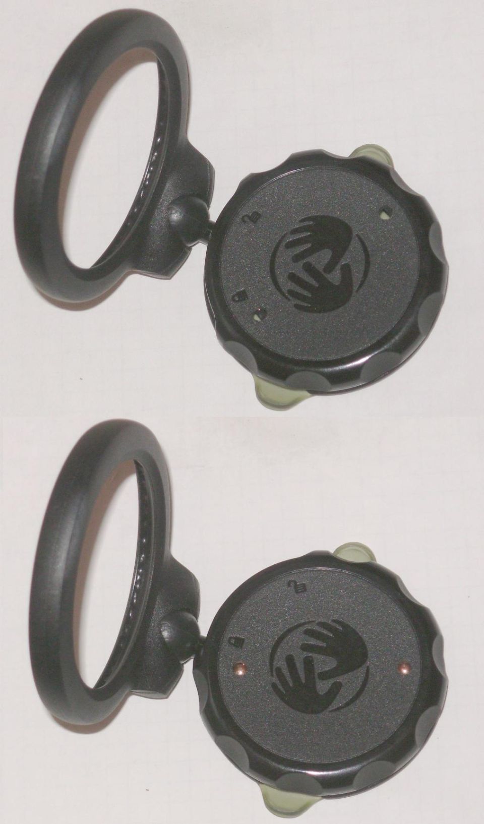 Two identical black parts, each with a loop and a circular dial a two-hand logo