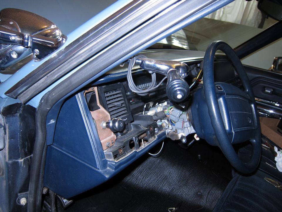 Car interior showing the dashboard, steering wheel, and center console area with some wiring exposed